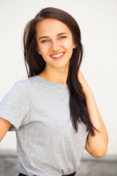 Happy Beautiful brunette woman in gray t-shirt, isolated on white wall background - 写真・画像