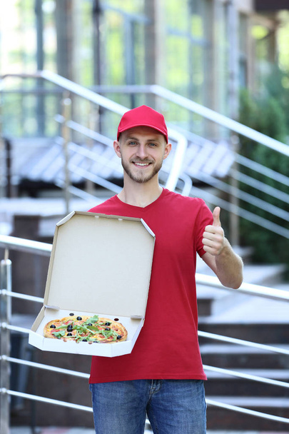 Delivery man with pizza in cardboard box - 写真・画像