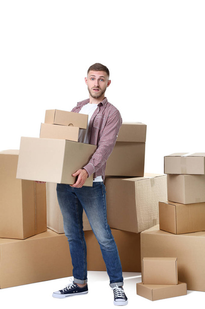 Young man with cardboard boxes on white background - Fotoğraf, Görsel