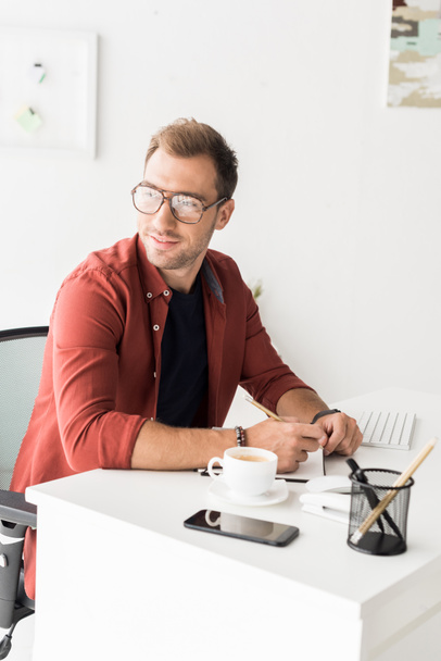 handsome businessman in glasses looking away in modern office  - Фото, зображення