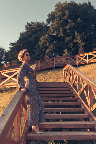 Mulher de pé nas escadas no parque ecológico urbano no pôr do sol
 - Foto, Imagem