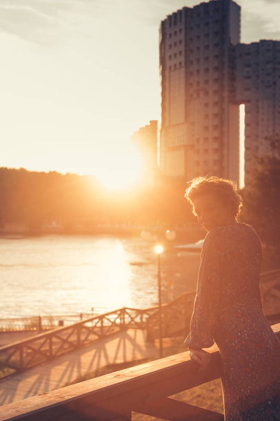 Woman watching the sunset in a park on the river bank - Photo, Image