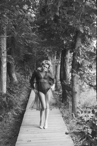 Retrato de uma mulher vestindo lingerie e babydoll, olhando para o lado, fotografado em um parque
 - Foto, Imagem