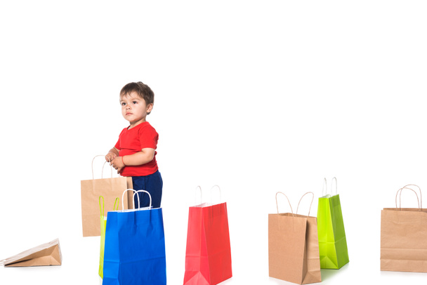lindo chico jugando con bolsas de compras aislado en blanco
 .  - Foto, Imagen