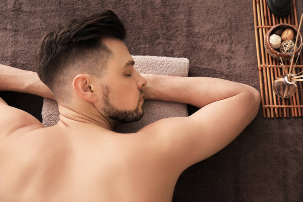 Giovane uomo rilassante sul lettino da massaggio nel salone spa
 - Foto, immagini