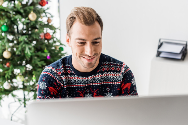 podnikatel v vánoční svetr pomocí počítače v moderní kanceláři   - Fotografie, Obrázek