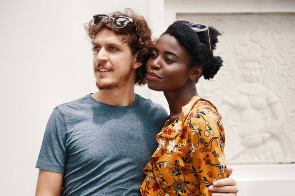 Schwarze Frau und kaukasischer Mann in sommerlichen Outfits stehen und umarmen - Foto, Bild