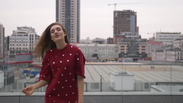 Chica atractiva en un vestido rojo va por la calle en una ciudad
 - Imágenes, Vídeo