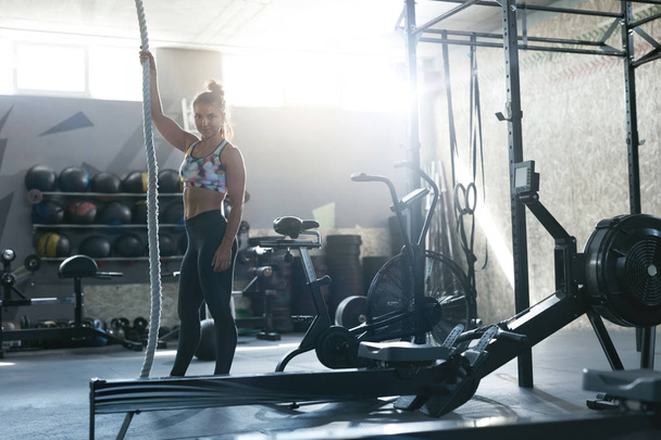 Training At Gym. Female Crossfit Athlete Climbing Rope - Фото, изображение