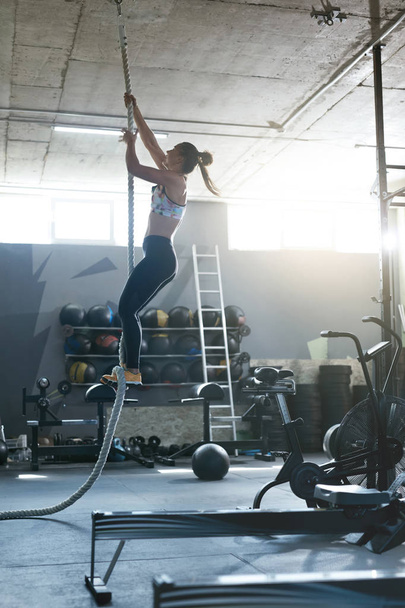 Training At Gym. Female Crossfit Athlete Climbing Rope - Foto, Imagem