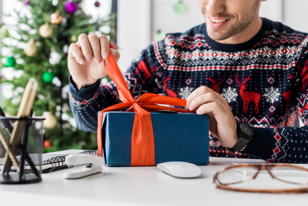 cropped view of businessman in christmas sweater opening gift box   - Foto, imagen
