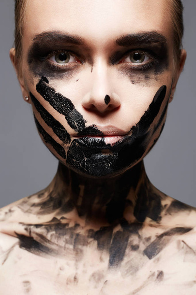 Krásná mladá žena s ukoptěným obličejem Paint. Malování na obličej a tělo. Dívka v černé barvy - Fotografie, Obrázek