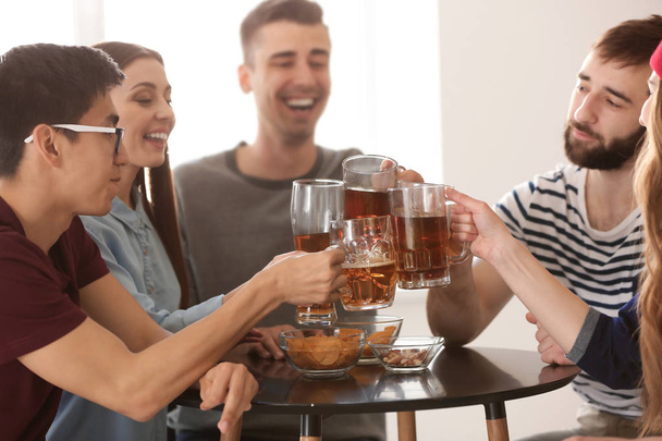 Groep vrienden rammelende brillen met bier in staaf - Foto, afbeelding