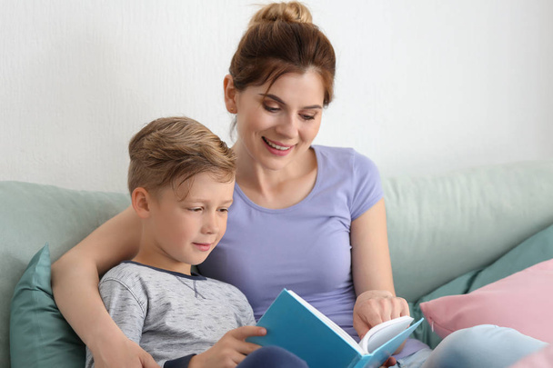 Mother and her son reading book together at home - Фото, изображение