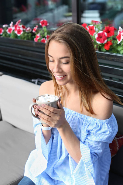 Beautiful young woman with cup of sweet cocoa drink in cafe - Foto, Imagem