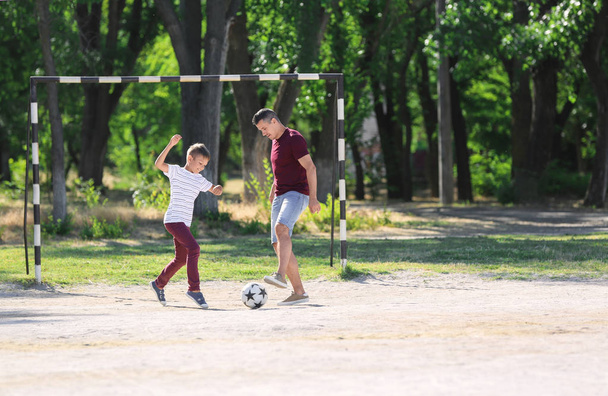 Menino com o pai a jogar futebol no campo de futebol
 - Foto, Imagem