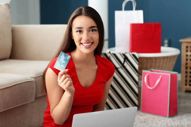 junge Frau kauft zu Hause online mit Kreditkarte und Laptop ein - Foto, Bild
