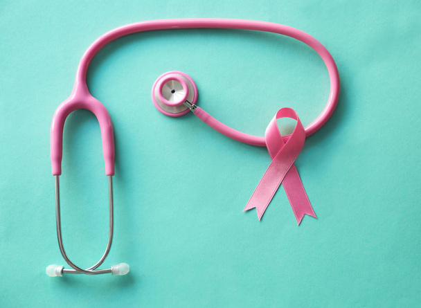 Pink ribbon and stethoscope on color background. Breast cancer awareness concept - Photo, Image
