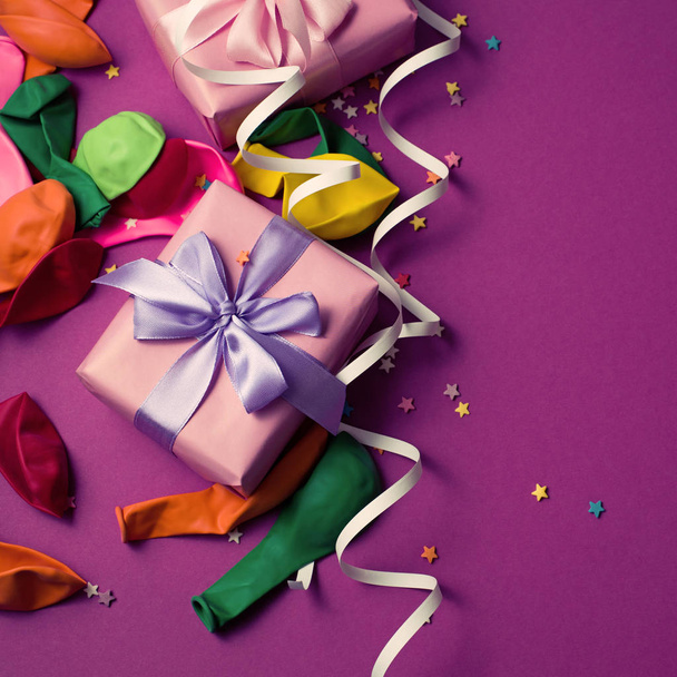 Ünnepi háttér lila anyag színes szerpentin konfetti két doboz ajándék lufi. Felülnézet lapos laikus másol hely - Fotó, kép