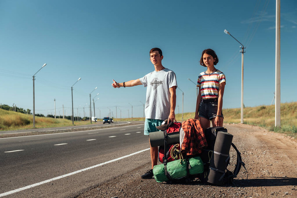 Autostop coppia. Backpackers su strada
 - Foto, immagini