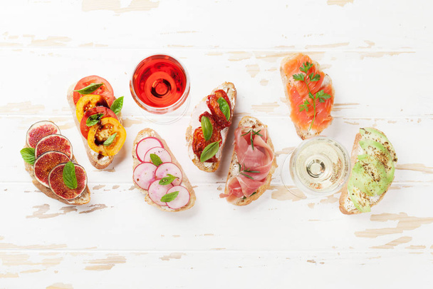 Appetizers italian antipasti snacks set on wooden board with rose and white wine. Top view and flat lay - Photo, Image