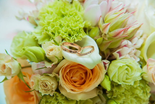 Wedding ring. Two gold rings with diamonds bride and groom and a bouquet of delicate flowers. - Фото, зображення
