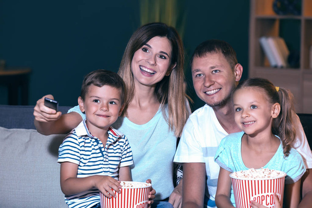 Happy family eating popcorn while watching TV in evening - Φωτογραφία, εικόνα