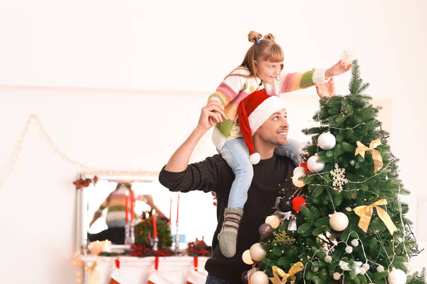 Cute girl with father decorating Christmas tree in room - Φωτογραφία, εικόνα
