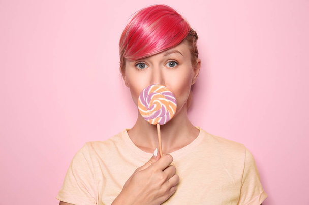 Beautiful young woman with unusual hair and lollipop on color background - Фото, изображение