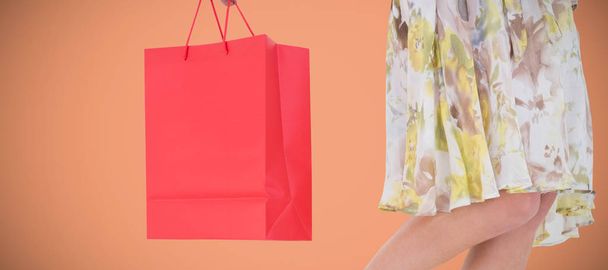 Elegant woman holding shopping bag against orange background - Foto, imagen