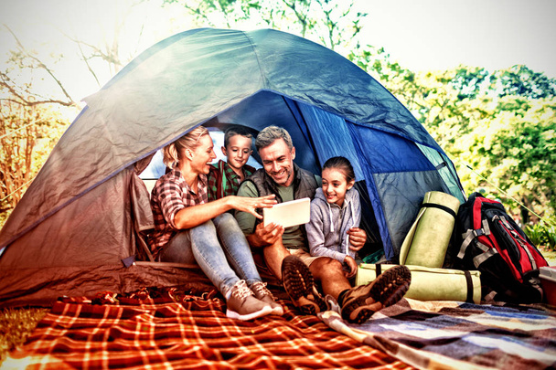 Família sorrindo olhando para o tablet digital na tenda
 - Foto, Imagem