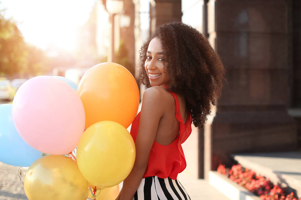 Beautiful African-American woman with balloons outdoors - Photo, Image