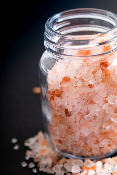 Концепция здорового питания розовая гималайская соль в стеклянной банке на фоне черного камня с чистого листа
 - Фото, изображение
