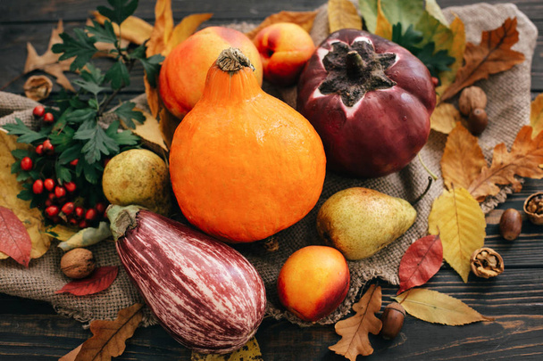 Beautiful Pumpkin, vegetables on bright autumn leaves, acorns, nuts on wooden rustic table. Space for text. Fall season greeting card. Atmospheric image. Happy Thanksgiving concept. - Photo, Image