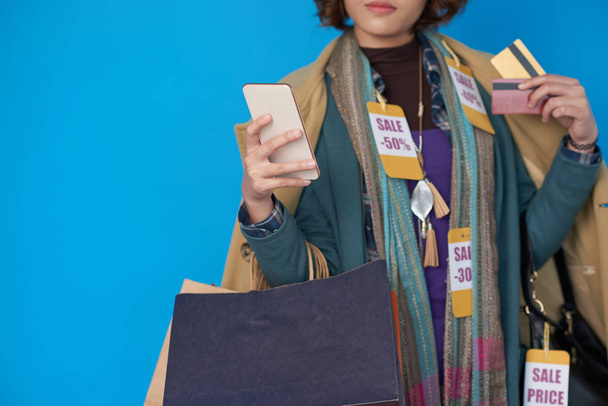 Asijské shopaholic žena pózuje s nákupní tašky, kreditní karty a mobilní  - Fotografie, Obrázek