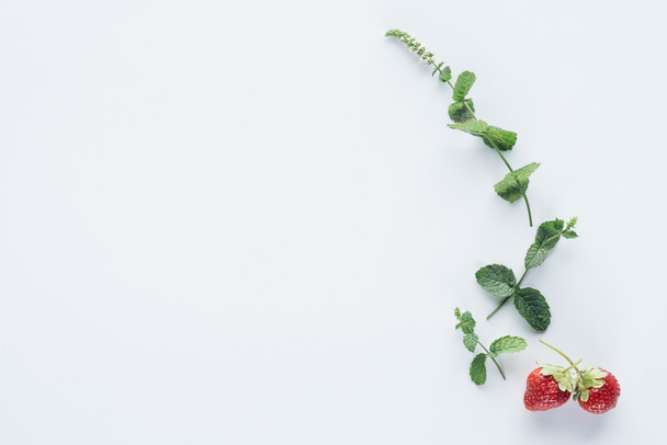 top view of strawberries and mint branches on white surface - Foto, Imagem