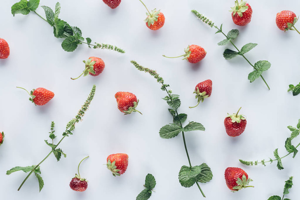top view of strawberries with mint leaves on white surface - Foto, imagen