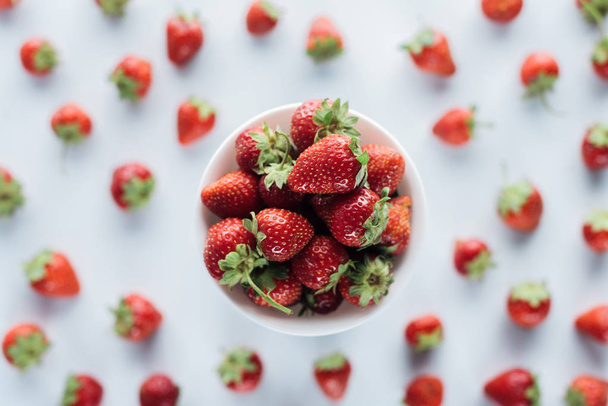 top view of bowl of fresh whole strawberries on white tabletop - Valokuva, kuva
