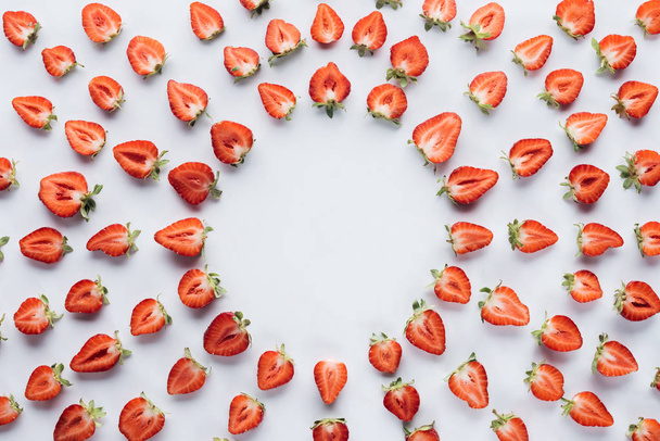 top view of round frame of ripe halved strawberries on white surface - Foto, immagini
