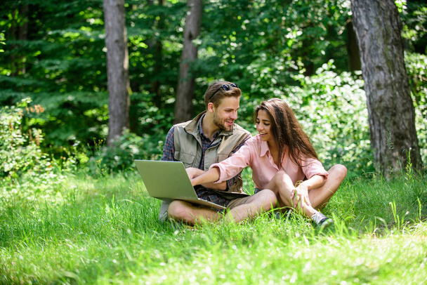 Closer to nature. Modern technologies give opportunity to be online and work in any environment conditions. Couple youth spend leisure outdoors with laptop. Man and girl looking at laptop screen - Photo, Image