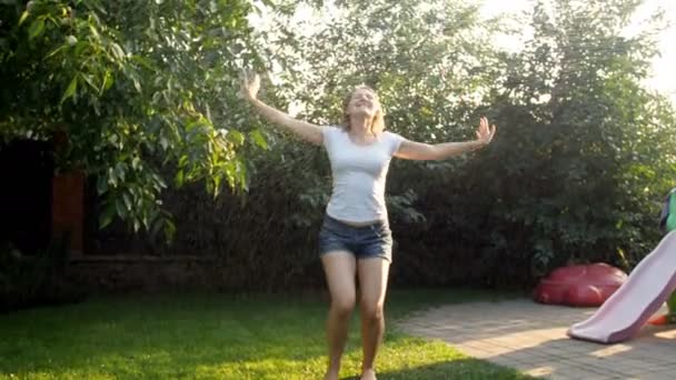 4 k videó a gyönyörű fiatal nő, a füvet a kertjében a nyári nap meleg eső táncol - Felvétel, videó