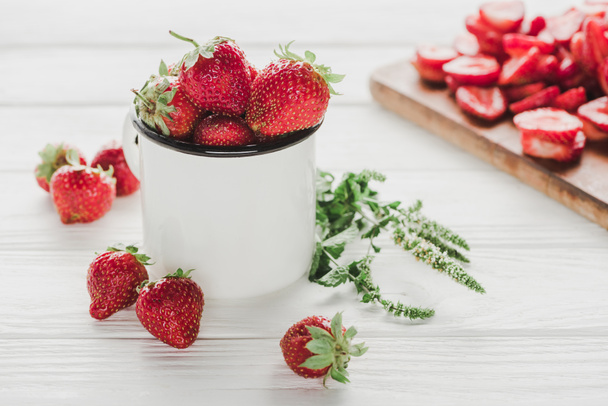 ripe strawberries in mug on white wooden surface with cutting board - Photo, Image