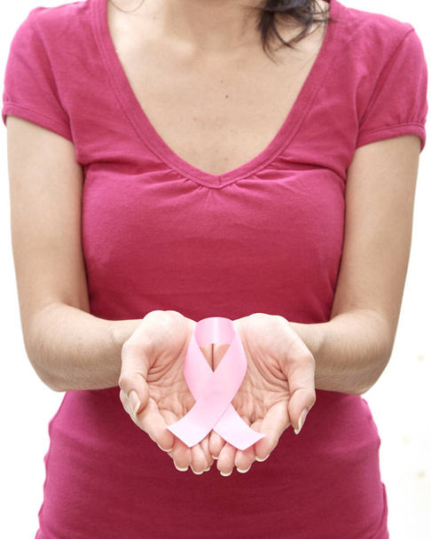 Χαμογελαστό γυναίκα με κορδέλα ευαισθητοποίησης του καρκίνου του μαστού σε άσπρο φόντο - Φωτογραφία, εικόνα