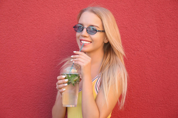 Belle jeune femme avec tasse en plastique de cocktail frais sur fond de couleur
 - Photo, image