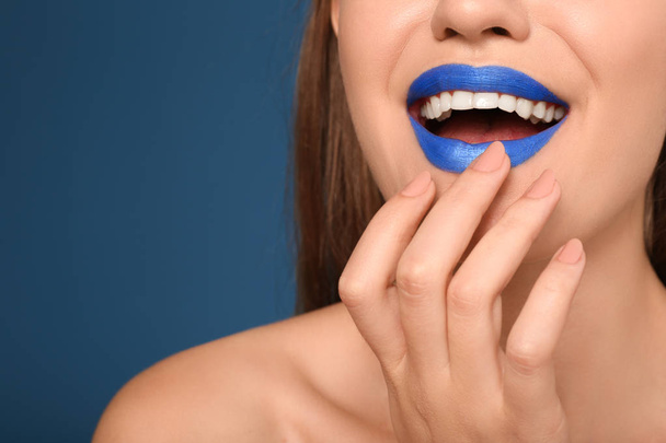 Beautiful young woman with unusual lipstick on color background, closeup - 写真・画像