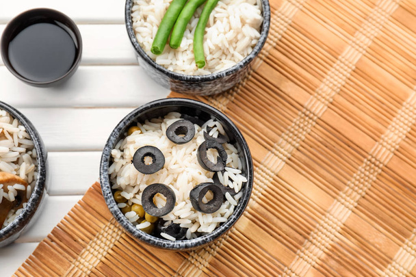 Miski z smaczne ugotowanego ryżu i warzyw na lekki drewniany stół - Zdjęcie, obraz
