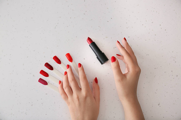 Female hands with stylish red nails and lipstick on light background - Photo, Image