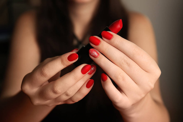 Mujer con elegantes uñas rojas sosteniendo lápiz labial, primer plano
 - Foto, imagen