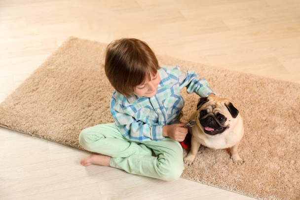 Μικρό αγόρι κάθεται με χαριτωμένο pug σκυλί στο πάτωμα στο σπίτι - Φωτογραφία, εικόνα