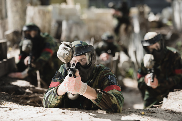 вибірковий фокус концентрованого гравця в захисній масці з маркерним пістолетом і його командою на фоні на відкритому повітрі
 - Фото, зображення